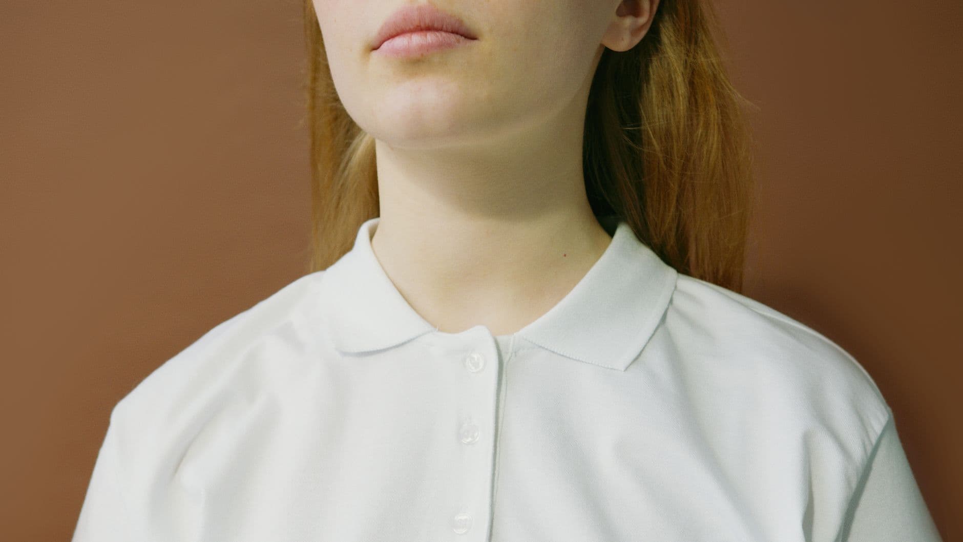 Pique Knit — Minimalist close-up photo of a woman in a white polo shirt with a neutral background.